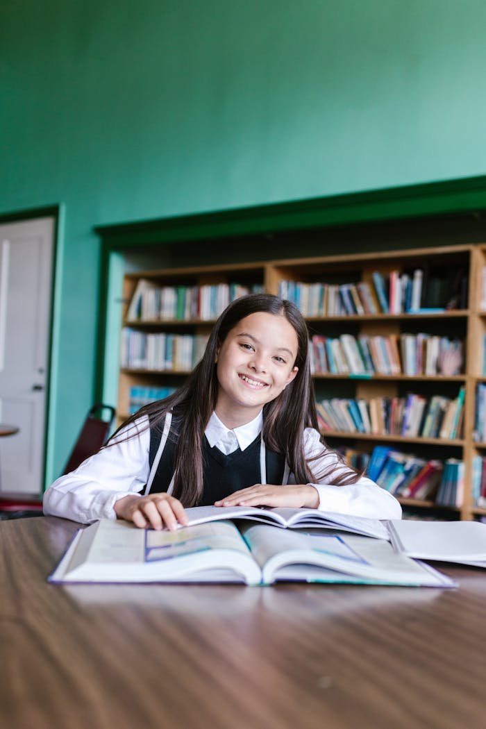 Young girl happily studying in a library, emphasizing education and learning.